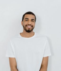Casual portrait of a smiling man in a minimalist white t-shirt with copy space on a plain background.
